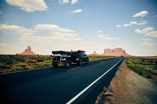 road black vehicle towing trailer on black road during daytime oljato-monument valley